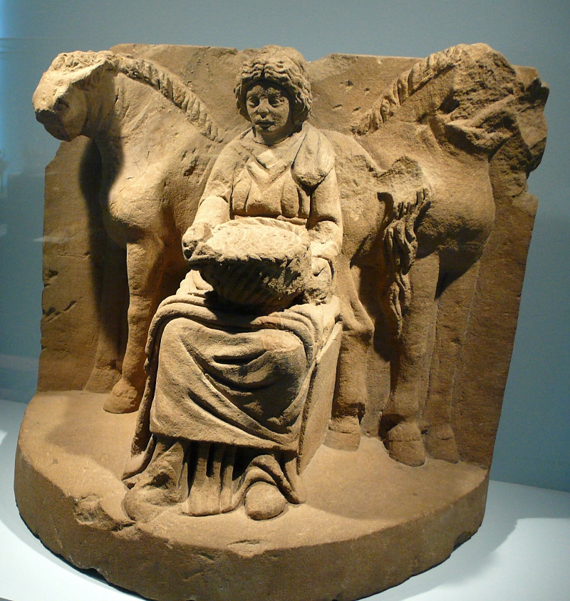 Flanked by two horses, Epona is shown sitting on a throne holding a fruit basket on her lap. The Celtic goddess was revered as the patroness for wagoners. Photo by Chez Casver, Wikimedia Commons